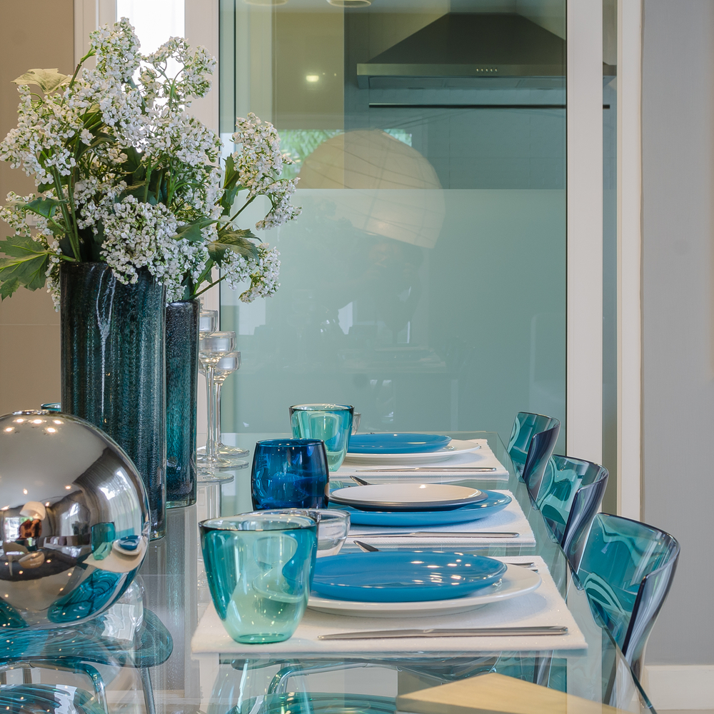 Mesa comedor de cristal con sillas transparente en color azul.