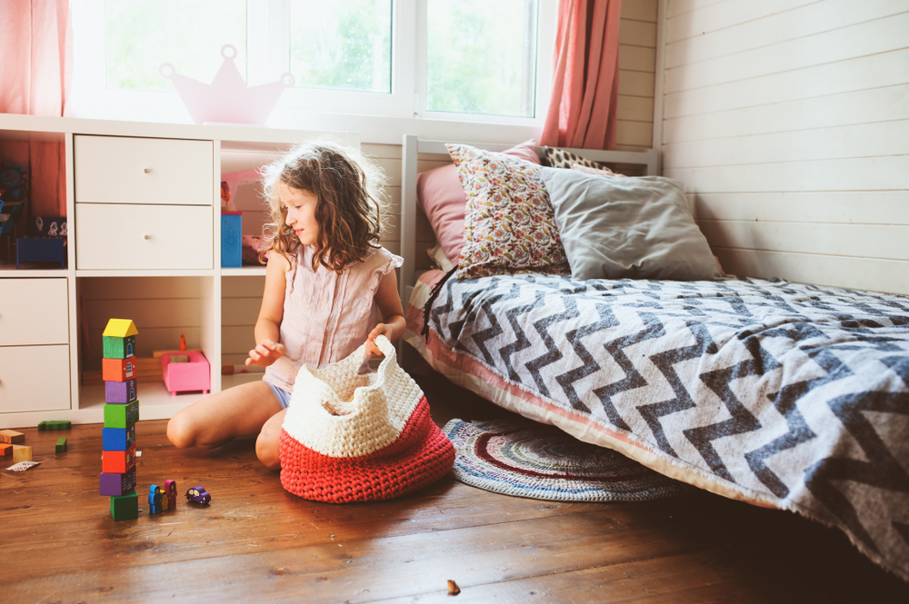 Niña pequeña ordenando su habitación.