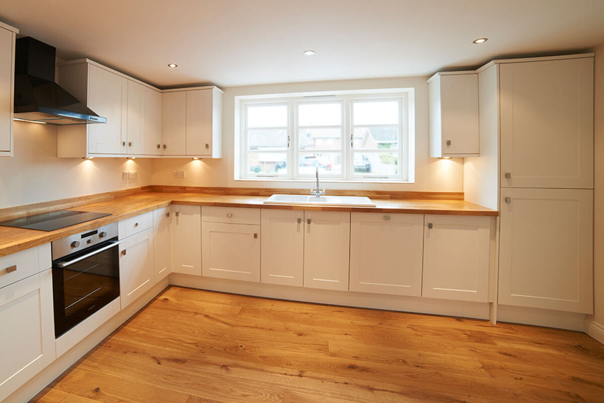 The wooden floor goes very well with the white kitchens.